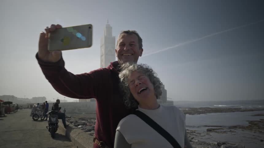 Tourist couple taking a selfie next to a lake and a temple in the background