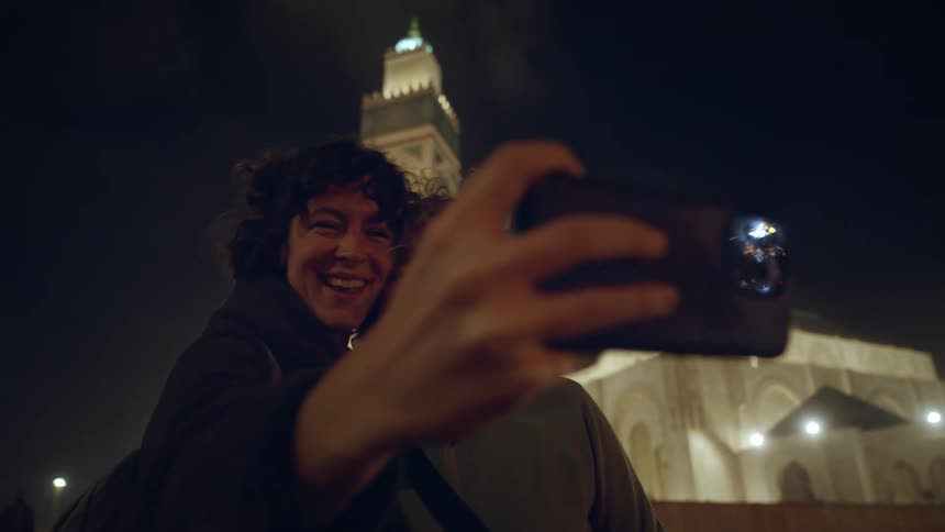 Twp women take a selfie in front of a tower at night