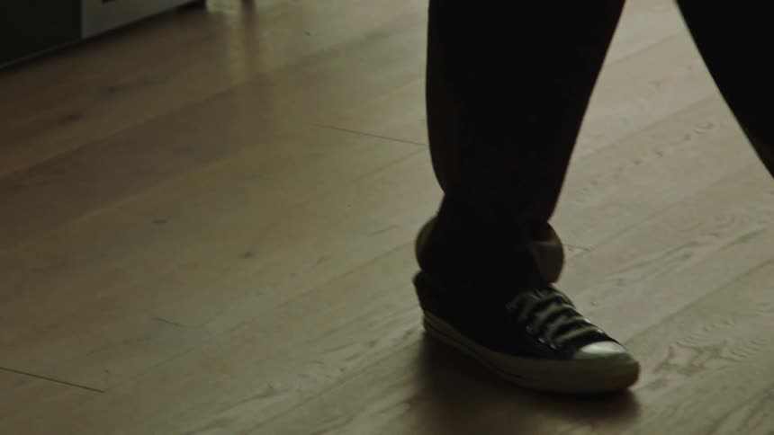 A male is walking around a building that has hardwood flooring