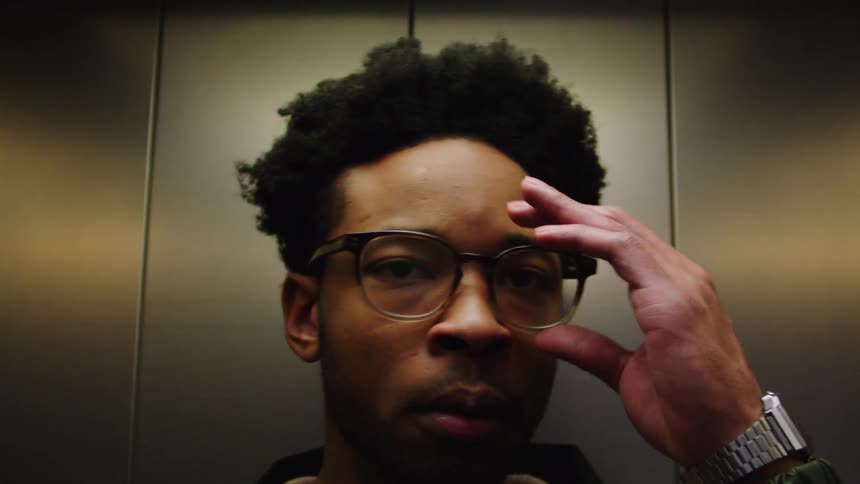 Portrait of a man inside the elevator adjusting his glasses and leaving