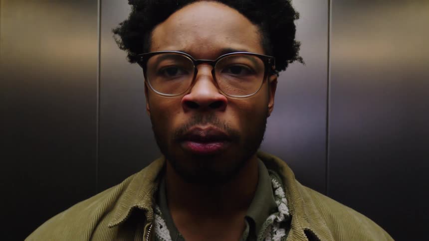 A man is waiting in an elevator and checking his wristwatch
