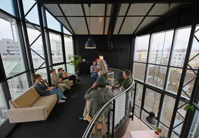 Group of people sitting in armchairs in an office environment with one of the people handing them a cup of coffee