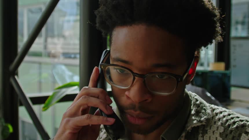 A close up pic of a mans face making a cellphone call