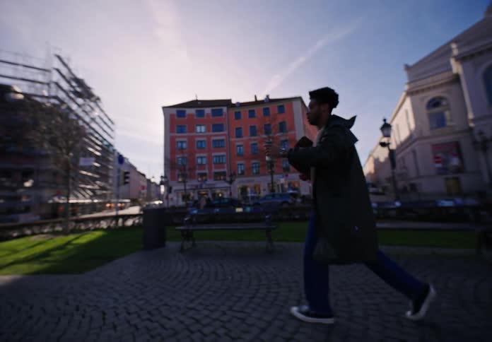 A young man running through a park in the city with a cup of coffee