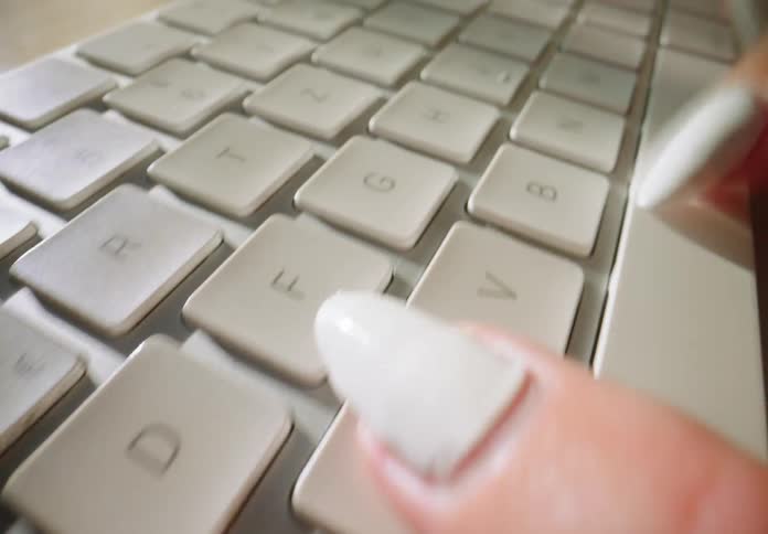 A woman is typing fast on a keyboard for a computer