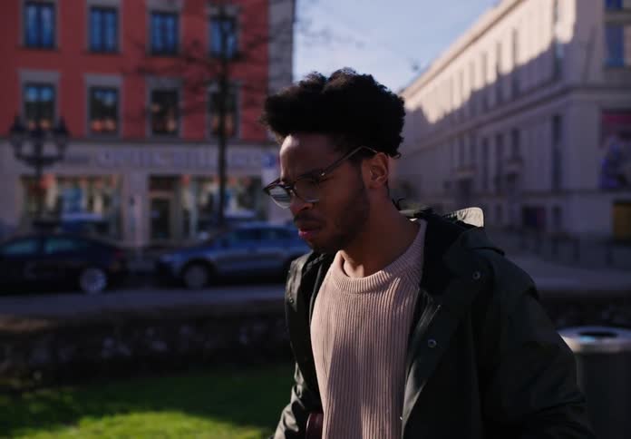A young man running through a park in the city with a coffee cup in his hand