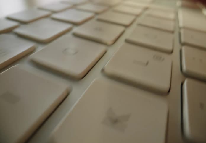 Female is typing on a computer keyboard during daylight