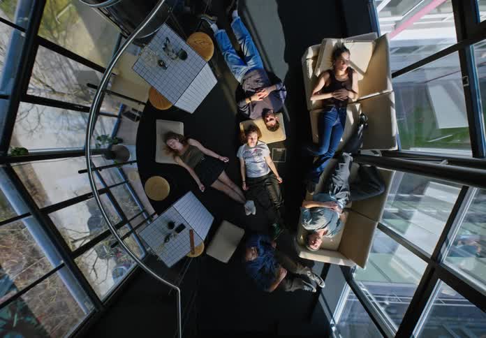 Young adults lying on the floor and sofa in an office building