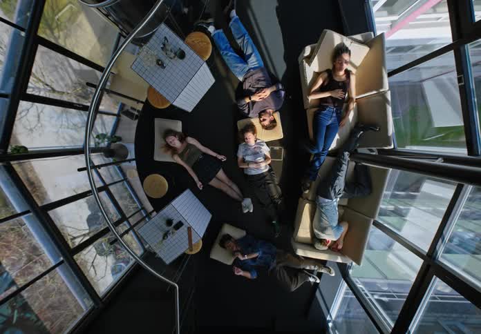 Friends lying on the floor and on the sofa sleeping in a mirrored office building
