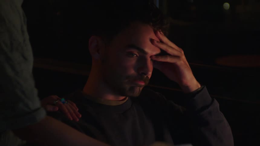 Portrait of a man sitting at an office desk with a discouraged facial expression and then a woman hands him tax coupon bills
