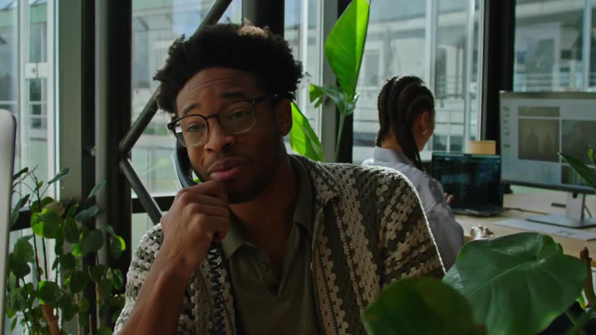 Co workers talk and laugh the man calls someone a worried look on his face