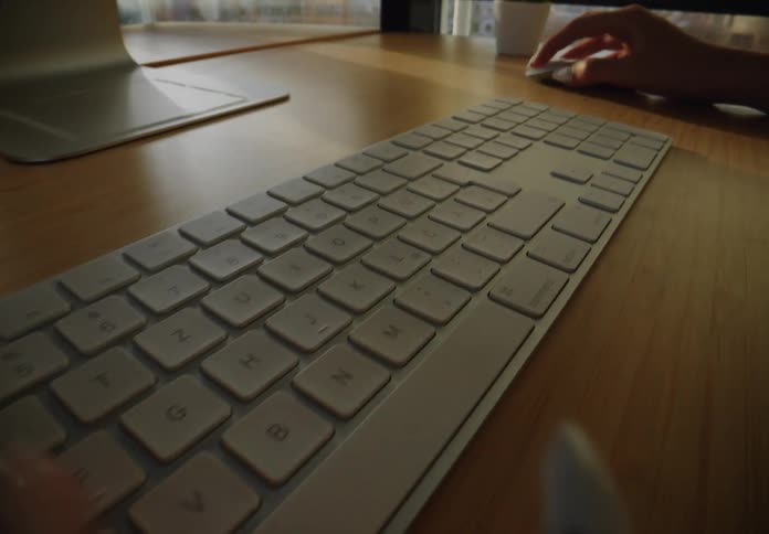 A woman is sitting at a computer and typing on a keyboard