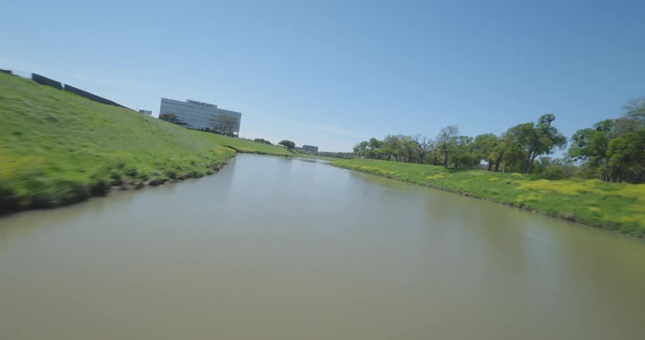 Drone footage flying under a bridge over a river on a clear day