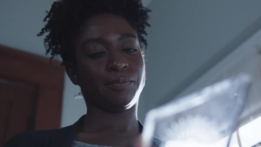 A woman is standing inside a room and looking at an object