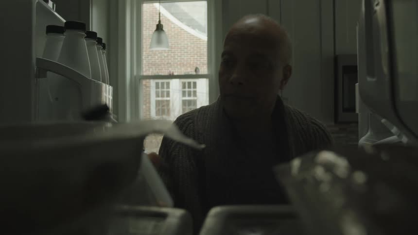 Point of view from inside the refrigerator and a man opening and taking a plastic bottle
