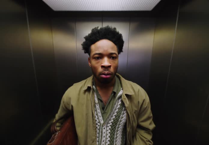A man is waiting in an elevator holding his briefcase