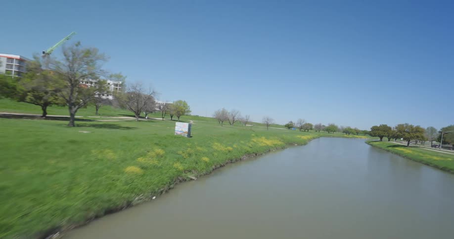 Panorama of a park with river canal and a bridge over it by the metropolitan city during a cloudless blue sky day