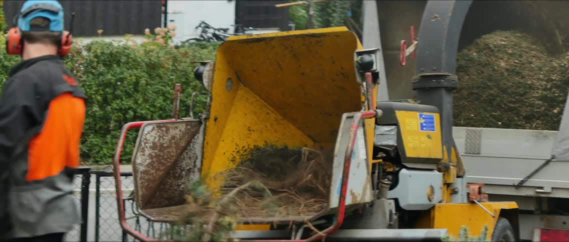 Men putting tree branches into a crusher