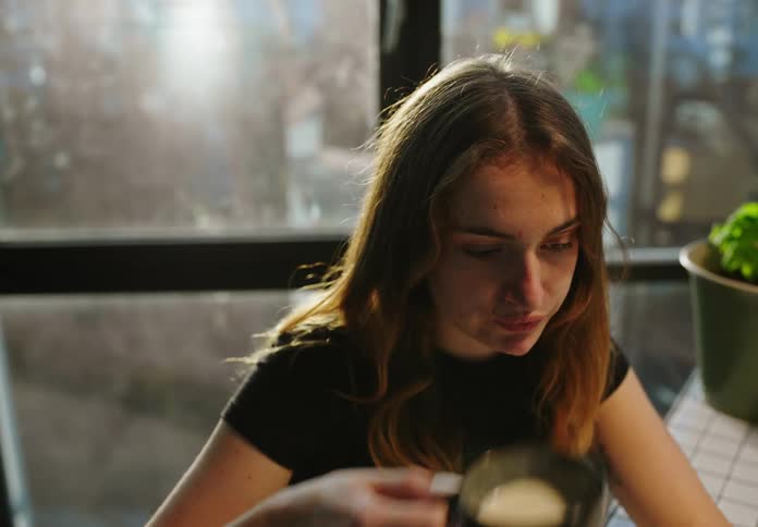 Young woman working at the office drinks coffee on a cup
