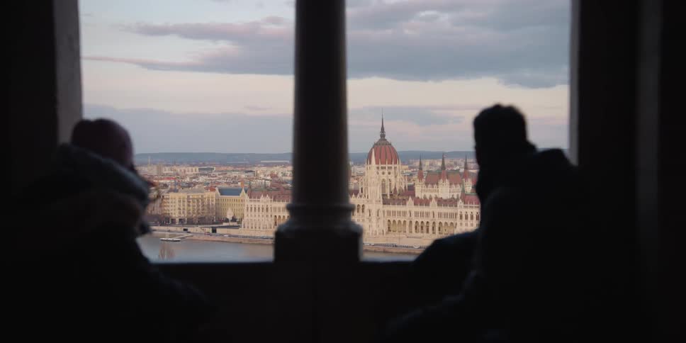 Two people enjoying the view of Budapest over the Danube through the window
