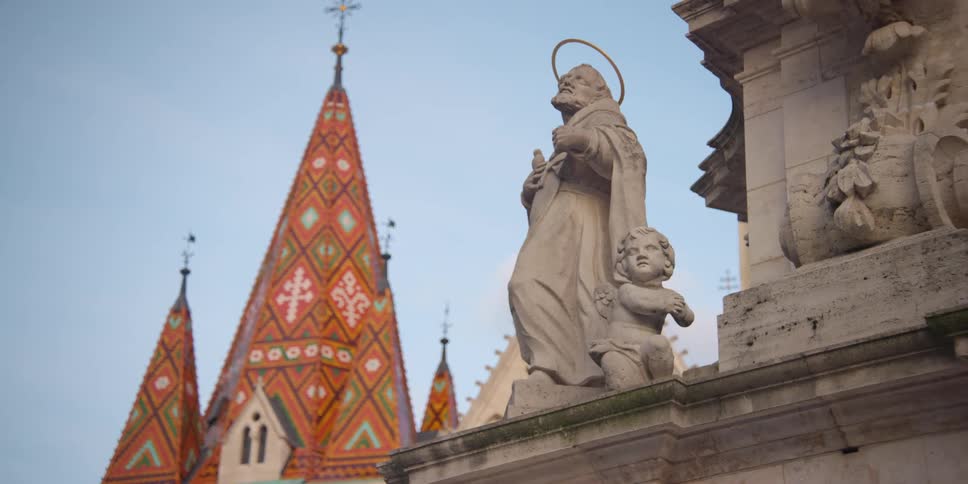 Holy Trinity Statue figures in front of Matthias Church colored tile roof in Budapest