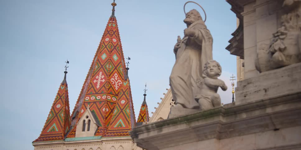 Holy Trinity Statue figures in front of Matthias Church colored tile roof in Budapest