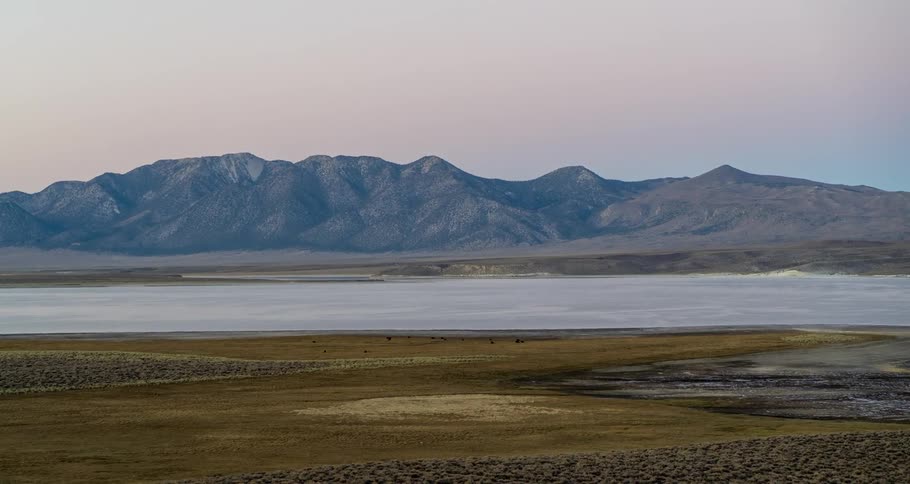 A giant mountain range dominates the surrounding body of water and plains