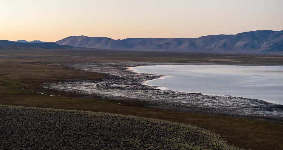 Aerial view of a lake next to a mountain range at dawn