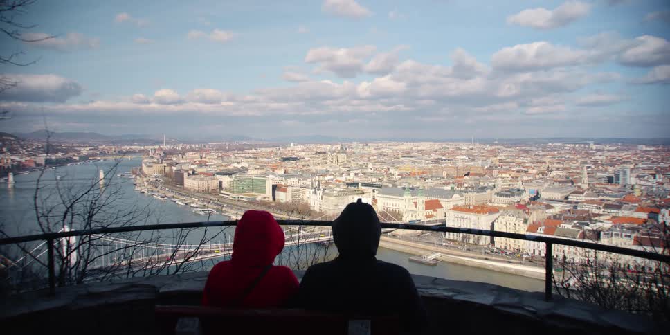 Two people sit and take in an expansive view of Budapest