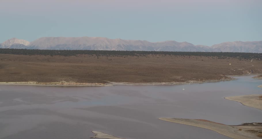 Panorama of a river surrounded by desert soil with mountain ranges on the horizon
