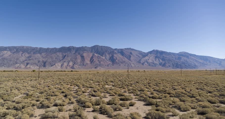 An aerial view of a desert landscape with rugged mountains in the background