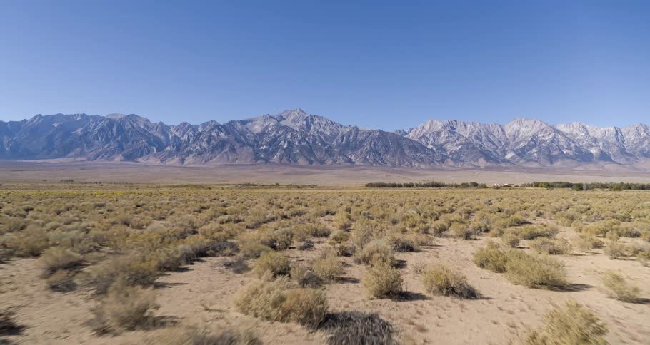 An aerial view of a desert landscape with rugged mountains in the background