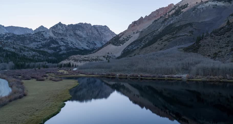Several tall mountains surround a reflective lake in the valley below