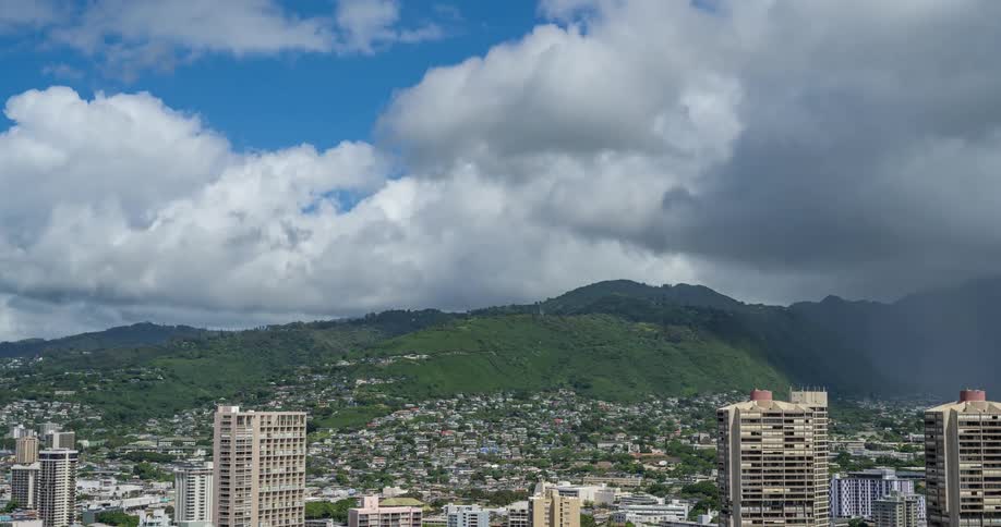 Clouds moving through the sky cast shadows onto city partially on the mountainside
