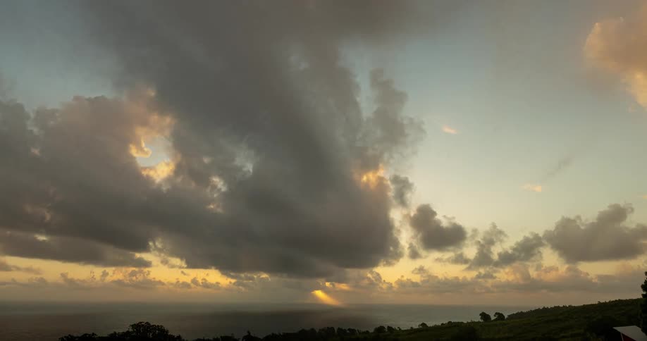 Time lapse of clouds rolling over a hill and the ocean next to it