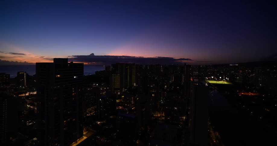 Sun moves across the sky until nightfall over a coastal city bisected by a river