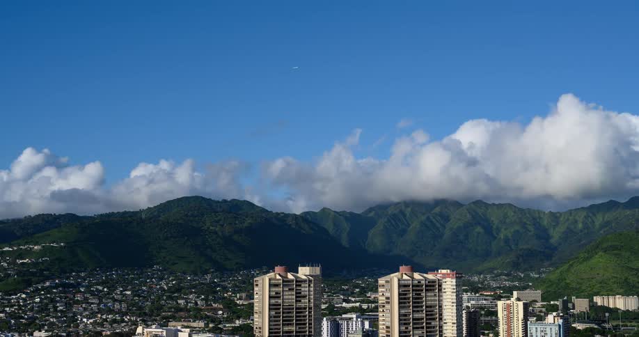 Clouds move over mountains near city