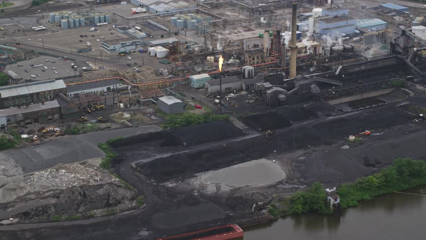 Aerial panorama of an industry with fire funnel and chimneys on the edge of a river canal