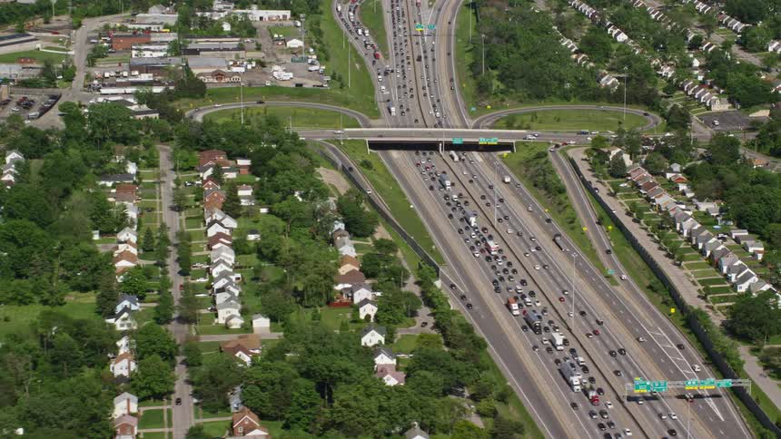 Aerial panorama of an urban city with residential neighborhoods on the side of highways with vehicle traffic during the day