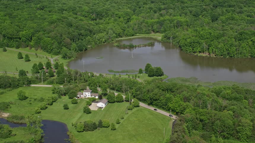 An aerial view of a house and a lake surrounded by trees
