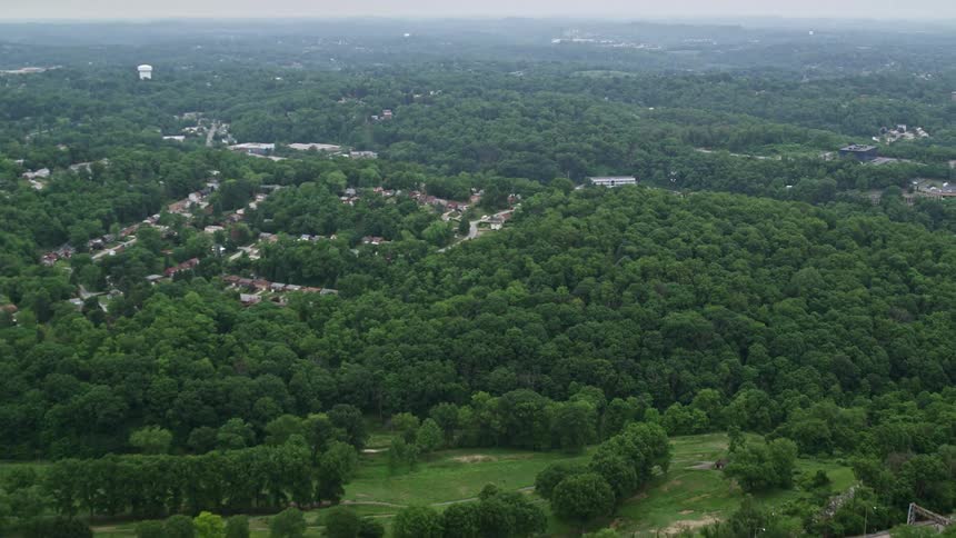 Aerial panorama of hills with forests and an urban city and in the middle a highway with vehicle traffic
