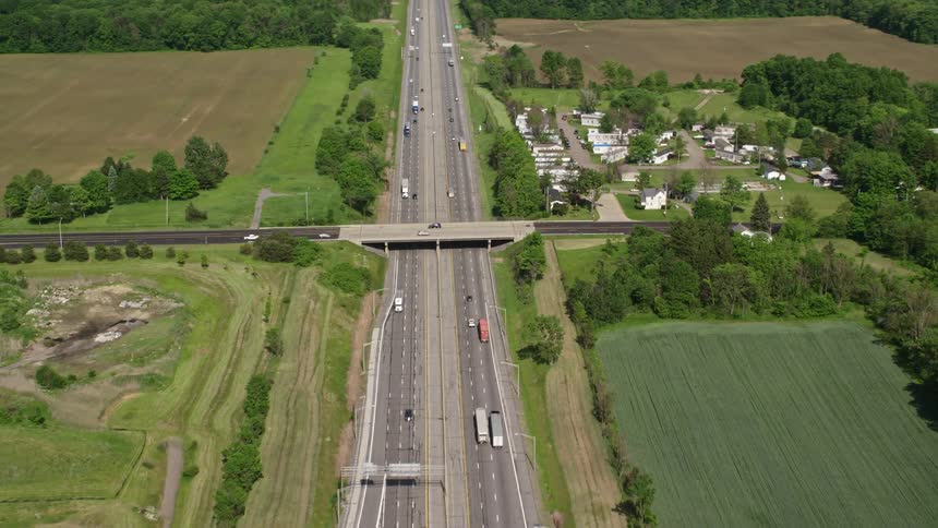 Aerial view of a highway intersection surrounded by green fields and a small town