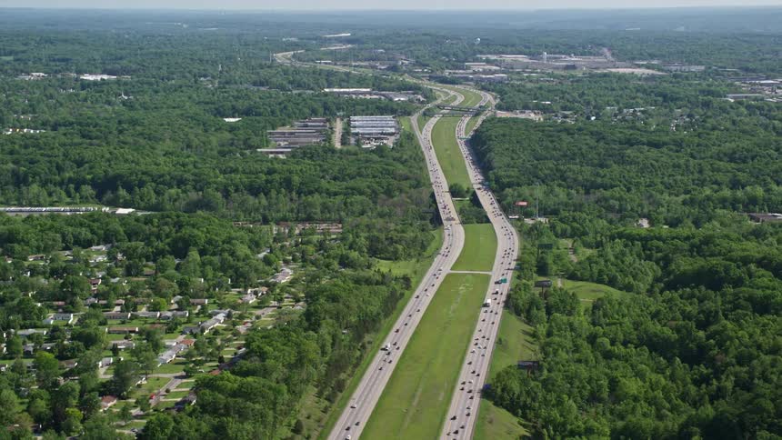Aerial panorama of a highway with vehicle traffic and surrounding residential neighborhoods with vast vegetation of trees