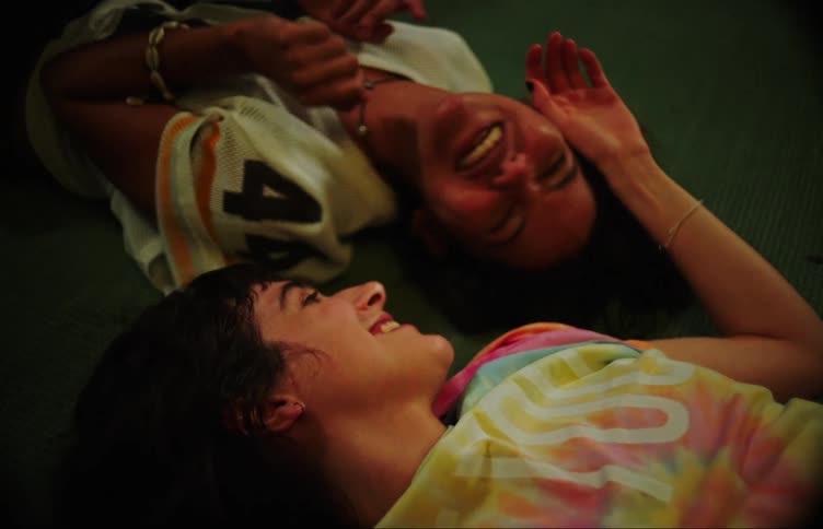 Two young women are lying on the floor engaged in lively conversation and laughter