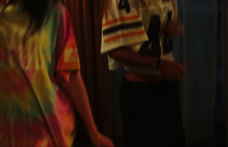 Two teenage girls dancing in a dimly lit room with colorful lights