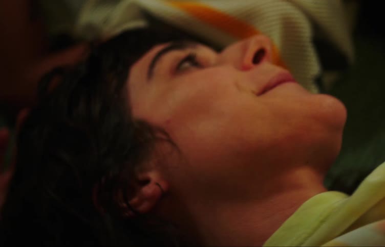 Portrait of two friends lying down looking at each other and smiling with one of them showing her tongue