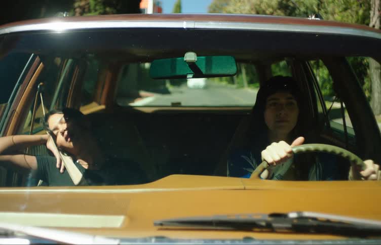 View from the windshield of a car of a woman driving and a young girl next to her sleeping