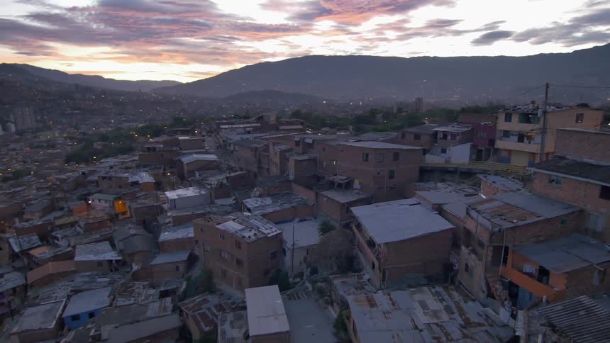 An aerial view of a very crowded city as the sun sets behind the mountains in the background