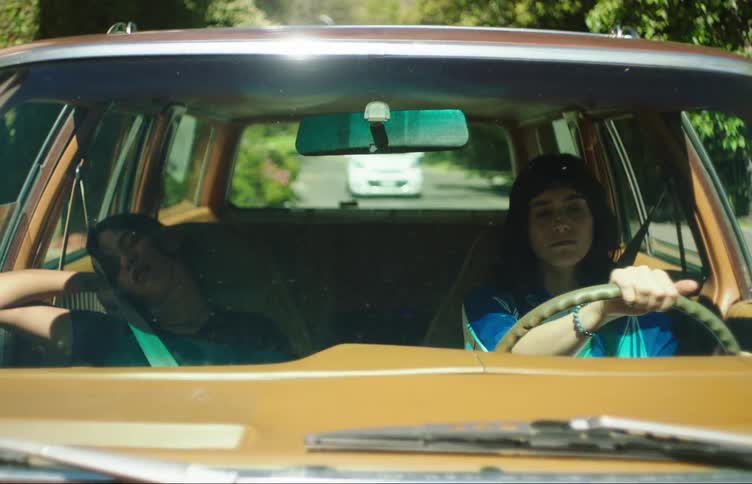 A lady driving whileher friend is sleeping in the car