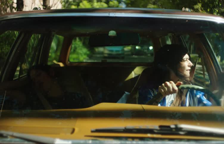 View from the windshield of a car of a stressed woman driving and fighting in traffic while another woman next to her is sleeping